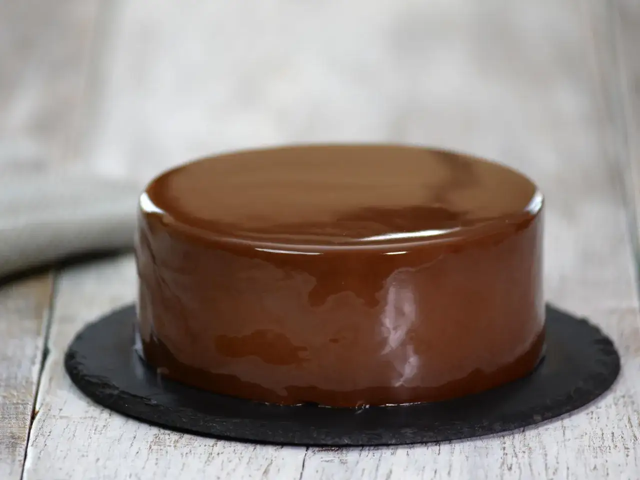 G&acirc;teau au chocolat avec gla&ccedil;age miroir, d'une brillance parfaite, pos&eacute; sur une ardoise.