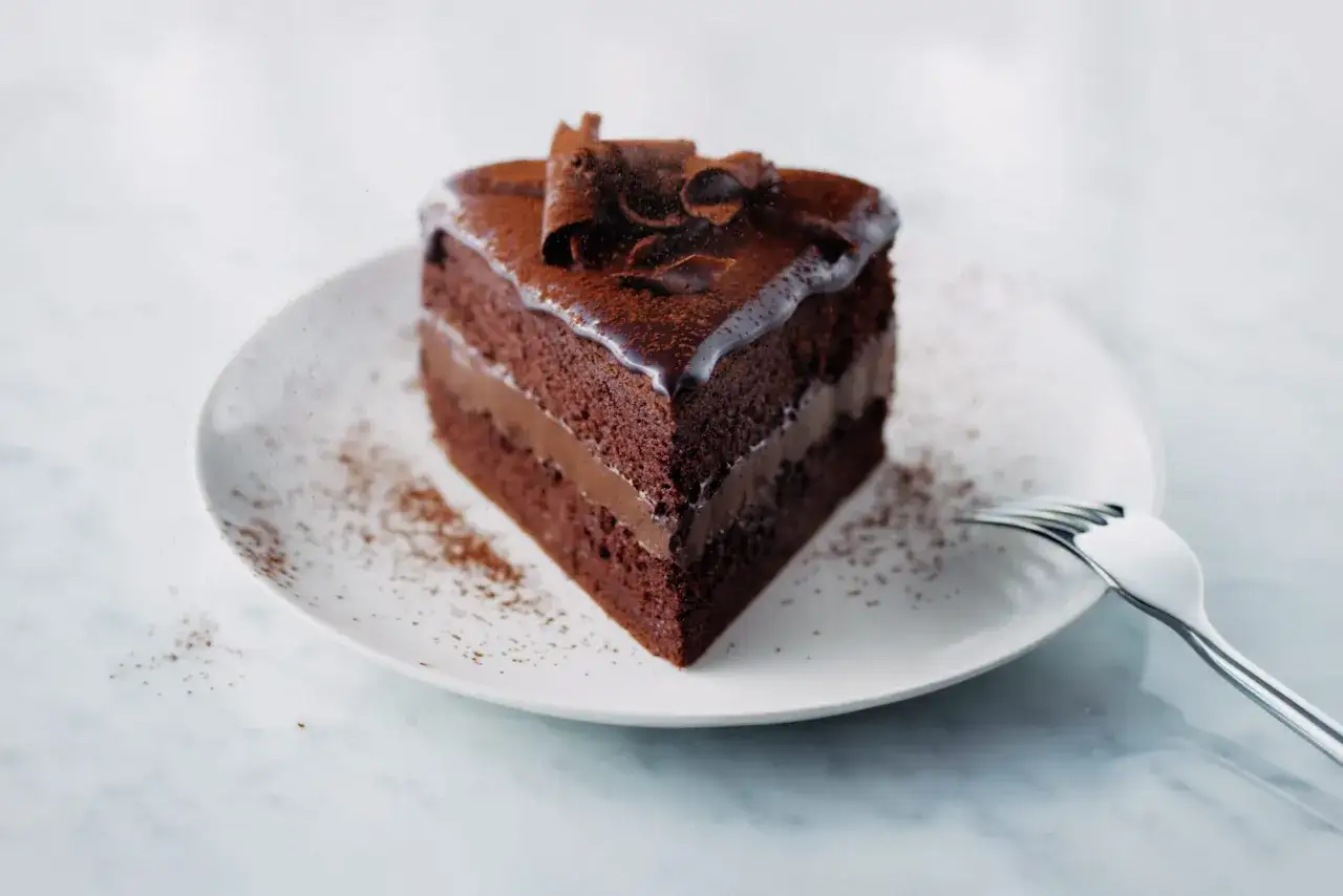 Tranche de g&acirc;teau genoise chocolat, avec gla&ccedil;age brillant et copeaux de chocolat. Un d&eacute;lice gourmand.