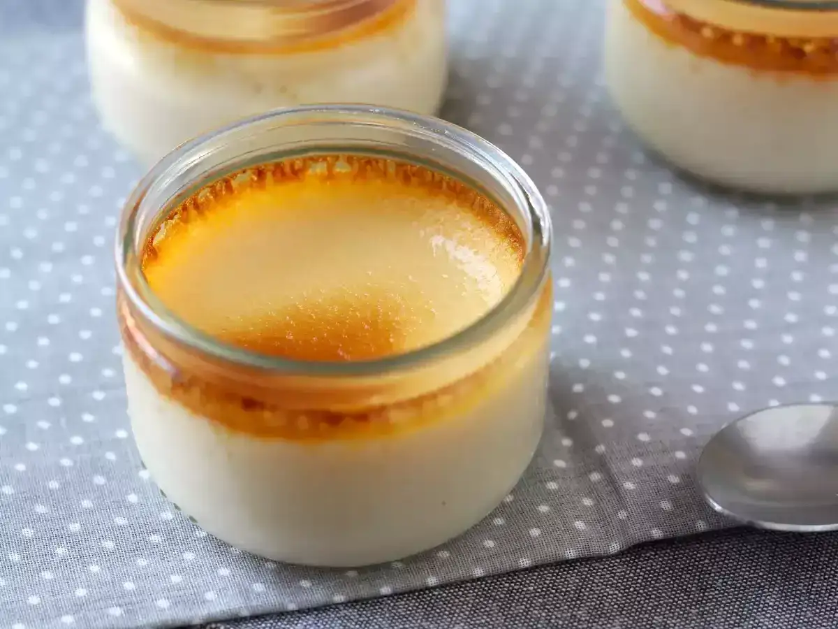 Crème brûlée maison, une recette dessert avec des oeufs, servie dans des petits pots en verre sur une nappe à pois.