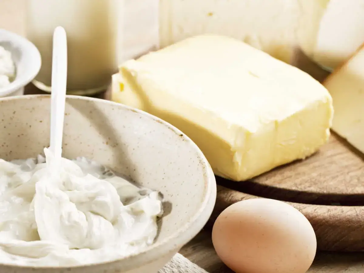 Crème fraîche on a spoon, un œuf, et du beurre. Une idée pour remplacer beurre par creme fraiche dans vos recettes.