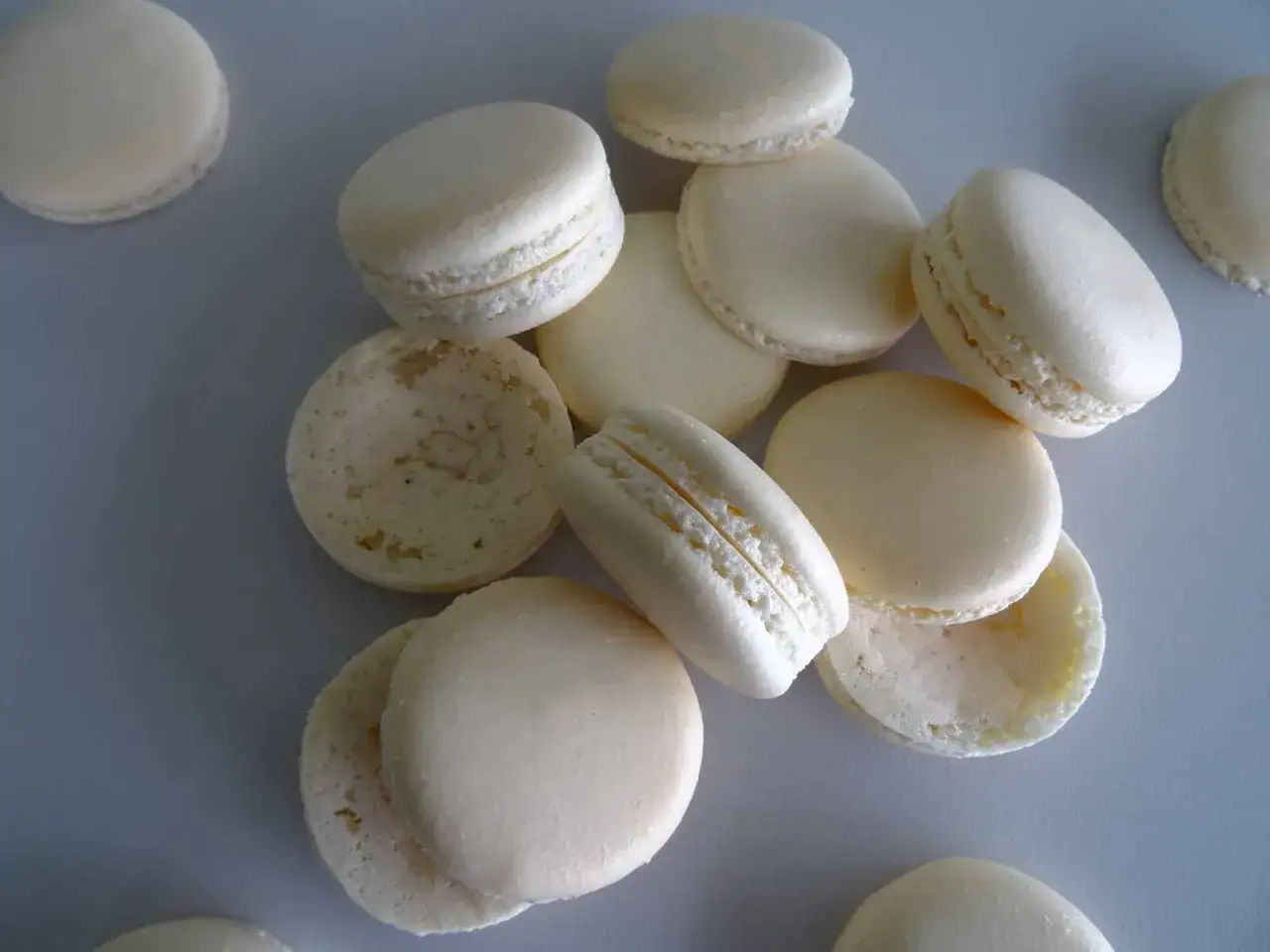 Un tas de macarons traditionnels, certains entiers, d'autres séparés, révèlent leur texture délicate.