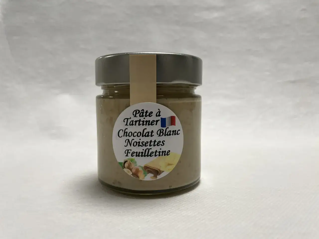 Un pot de pâte à tartiner chocolat blanc noisettes feuilletine, parfait pour une recette nocciolata bianca gourmande.