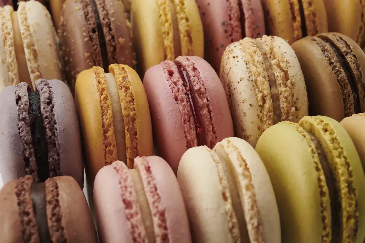 Assortiment de macarons aux couleurs vives, certains garnissent une ganache chocolat.