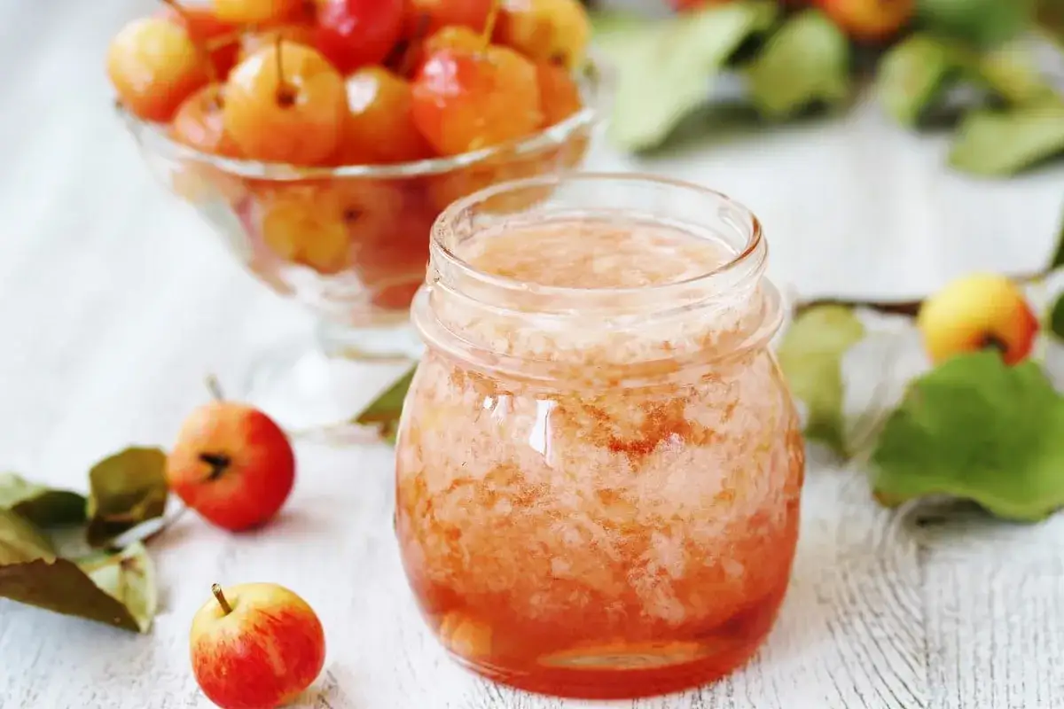 Confiture maison aux pommes, le dosage pectine NH est parfait pour une texture idéale. Petites pommes et pot de confiture sur fond blanc.