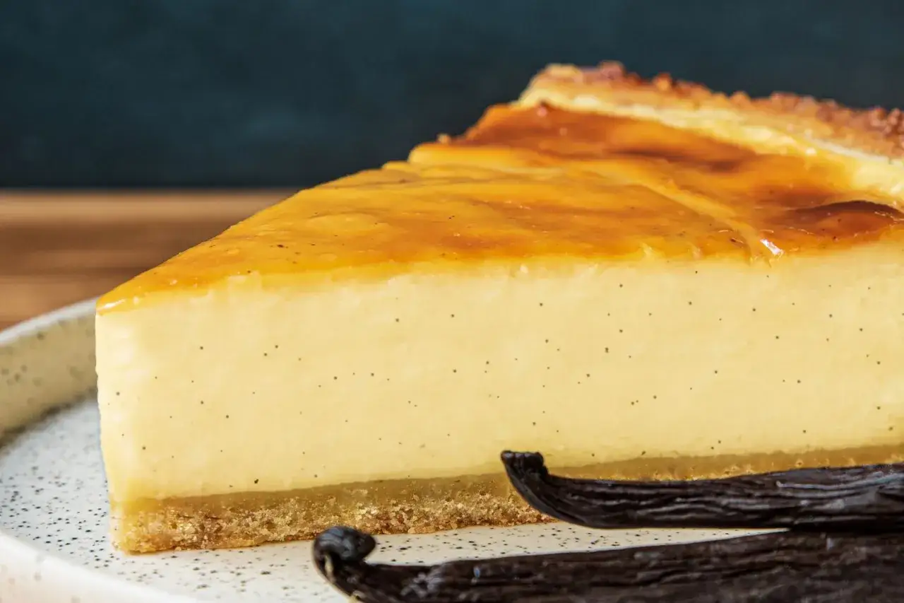 Tranche de flan &agrave; la vanille onctueux, parsem&eacute; de grains de vanille, avec une cro&ucirc;te dor&eacute;e et des gousses de vanille &agrave; proximit&eacute;.