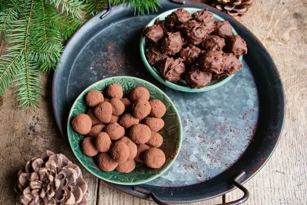 Deux assiettes de truffes au chocolat, certaines enrobées de cacao, d'autres de chocolat fondu. Parfait pour une recette des truffes au chocolat festive.