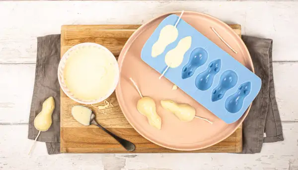 Préparation de **chocolat blanc** pour des souris en moule. Un bol de chocolat fondu, une cuillère, et des formes de souris en cours de fabrication.