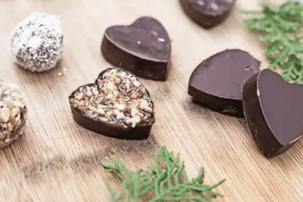 Chocolats maison en forme de cœur, certains garnis de noix, parfaits pour une recette petit chocolat maison facile.