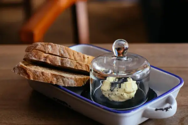 Tranches de pain artisanal avec une portion de beurre aux herbes, une excellente alternative par quoi remplacer le beurre.