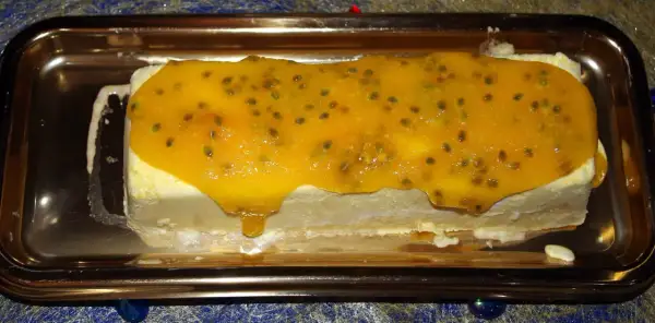 Gâteau glacé rectangulaire nappé d'un confit mangue passion aux graines visibles, sur un plateau doré.