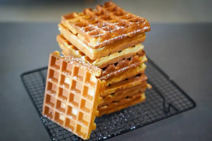 Pile de gaufres dorées saupoudrées de sucre glace, parfaites pour une recette gaufre levure chimique.